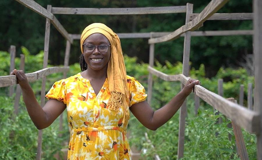 A Black woman smiling in a community garden